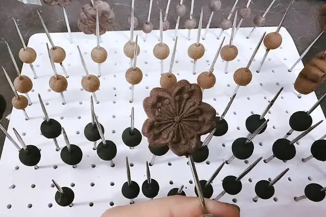 白色多孔板上插著多顆珠件，前景手持花形合香件